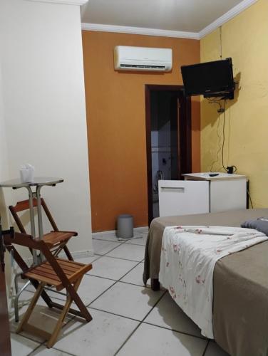 a room with a bed and a table and a chair at Pousada Pé na Praia in Rio das Ostras