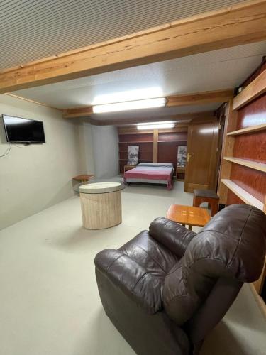 a living room with a leather couch and a bed at Habitaciones Espacio in Corbera de Alcira