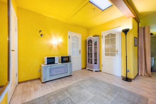 a living room with a yellow wall and a microwave at Gästehaus Ziegler in Neuenkirchen