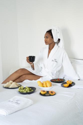 a woman sitting on a bed with plates of food at CL Group Guest House in Cacém