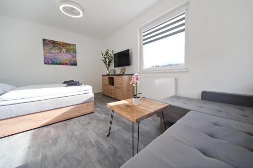 a white bedroom with a bed and a table at Bohemian Glow of Krumlov in Český Krumlov