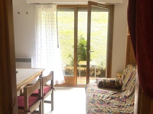 - un salon avec une table, un canapé et une fenêtre dans l'établissement Charmant T2 au pied des pistes, terrasse sud, proche commerces et télécabine - FR-1-573-35, à Saint-Jean-dʼAulps