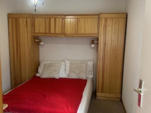 - une chambre avec un lit rouge et des placards en bois dans l'établissement Charmant T2 au pied des pistes, terrasse sud, proche commerces et télécabine - FR-1-573-35, à Saint-Jean-dʼAulps