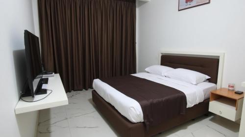 a bedroom with a bed and a desk with a television at Punarvika Bay Villa in Puttalam