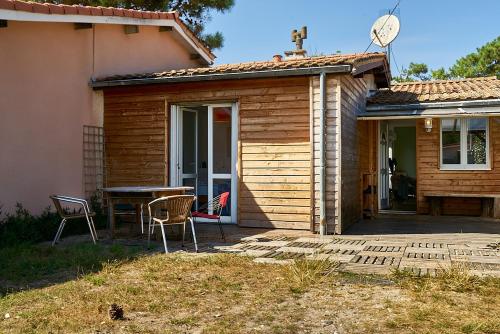 une maison avec un patio avec une table et des chaises dans l'établissement Maison LICORNE MARINE à 2 minutes à pied de la mer, à Lacanau
