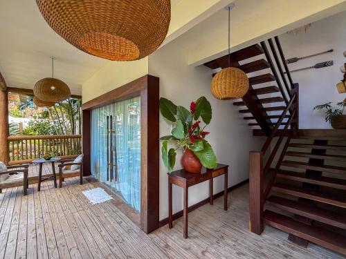 a living room with a staircase and a table with a plant at Pousada Recanto Caxando in Trancoso