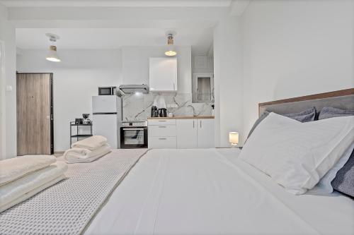 a white bedroom with a large bed and a kitchen at Athens Urban Lifestyle Apartments in Athens