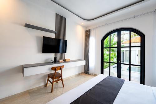 a bedroom with a bed and a desk with a tv at Majestic Balangan in Uluwatu