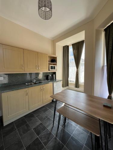 a kitchen with a wooden table and a dining room at Puffins Nest, close to Tunnels Beach & Harbour with Parking in Ilfracombe