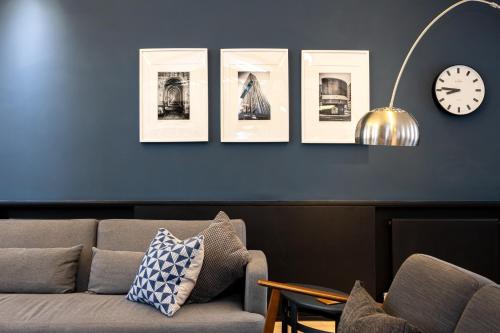 a living room with a couch and a clock on a wall at Central and Quirky Northern Quarter Flat, Manchester in Manchester