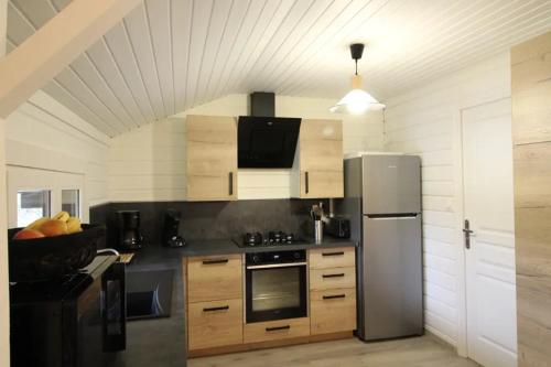 a kitchen with a stainless steel refrigerator and wooden cabinets at Chalet 6 personnes au Ménil - Vosges - Vacances nature en famille in Le Ménil