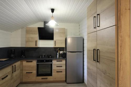 a kitchen with a stainless steel refrigerator and wooden cabinets at Chalet 6 personnes au Ménil - Vosges - Vacances nature en famille in Le Ménil