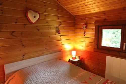 a bedroom with a bed in a wooden wall at Chalet 6 personnes au Ménil - Vosges - Vacances nature en famille in Le Ménil