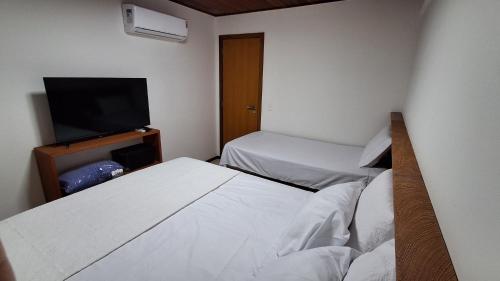 a room with two beds and a flat screen tv at Villa Andorinha, Apt 03 in Mucugê