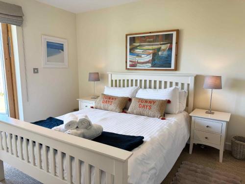 a white bed with a stuffed animal on it in a bedroom at House 32 in Looe