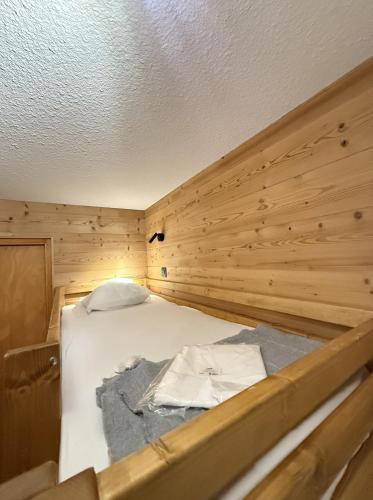 un lit dans une chambre avec un mur en bois dans l'établissement Appartement au pied des pistes, à Châtel