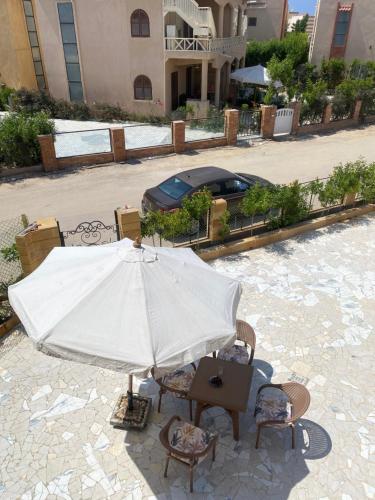 a patio with an umbrella and chairs and a table at Twin Villa with Private Garden & Rooftop at Orchidia Village Sidi Abdelrahman in El Alamein