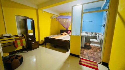 a yellow room with a bed and a window at Pick Me Village in Dambulla