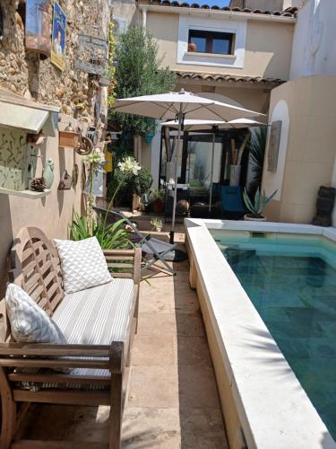 een zwembad met stoelen en een parasol naast een huis bij La Bohème in Eyragues