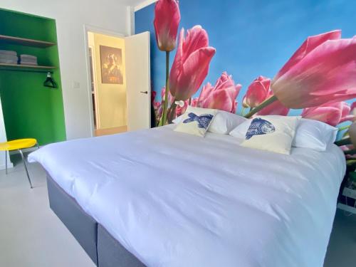 a bedroom with a white bed with pink flowers on it at Deining in Sint Maartensvlotbrug