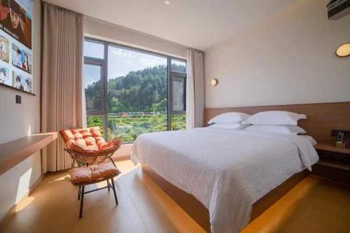 JiawanMountain and Bamboo Holiday Homestay Zhangjiajie Forest Park Branch的一间卧室，配有一张床、一把椅子和一扇大窗户