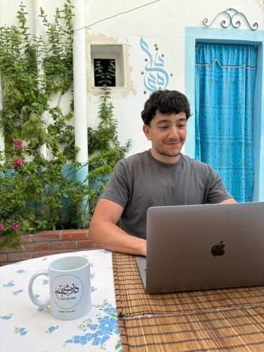 a man sitting at a table with a laptop computer at Dar Hkaïem in Sousse