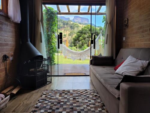 a living room with a couch and a large window at Chalé Petra - Recanto da Pedra in São Bento do Sapucaí