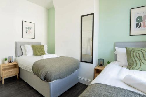 a bedroom with two beds and a mirror at 3 Bed House 9 mins walk to Anfield Sleeps 7 in Liverpool
