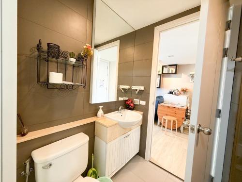 Un baño con inodoro, lavabo y espejo. en Finn Room Plus 38 sqm & The Patio by BHB, en Bangsaen Sai 1