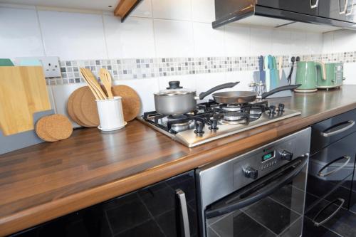 a kitchen with a stove with pots and pans on it at 3 Bed House 9 mins walk to Anfield Sleeps 7 in Liverpool