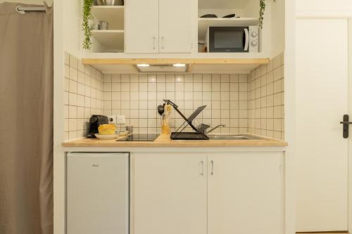 une cuisine avec des armoires blanches et un évier dans l'établissement Hyper centre, résové, lave linge, wifi, coin nuit séparé, à Dax