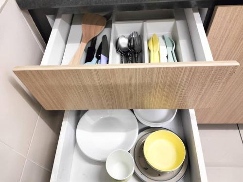 a cabinet filled with white plates and utensils at JB Austin Regency Simple N Tidy 5pax PLUS 1 in Johor Bahru