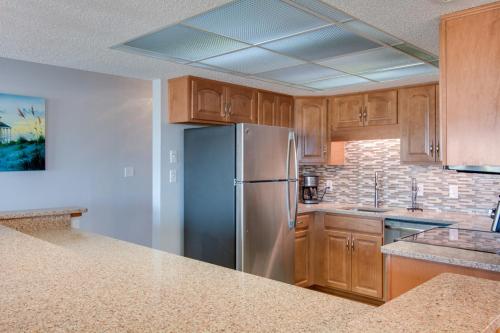 Una cocina con refrigerador de acero inoxidable y gabinetes de madera. en Heron Cove 104S, en Nags Head