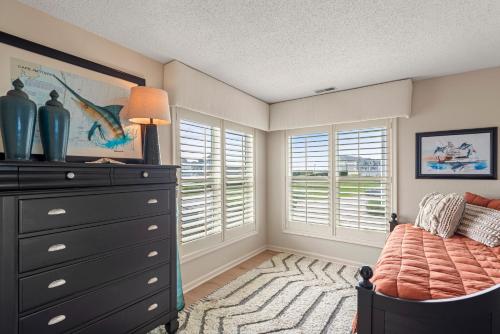 a bedroom with a bed and a dresser and windows at PC Beach in Manteo
