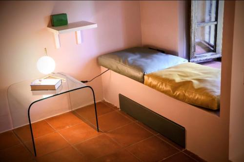 a small room with a bed and a table with a lamp at Romantic cozy house 15 min Arezzo piscina&bosco in Falciano