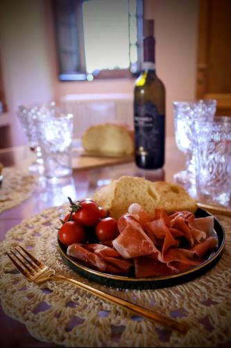 a plate of food on a table with a bottle of wine at Romantic cozy house 15 min Arezzo piscina&bosco in Falciano