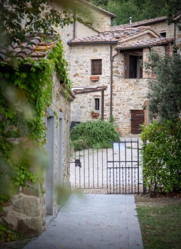 an entrance to a stone house with a gate at Romantic cozy house 15 min Arezzo piscina&bosco in Falciano