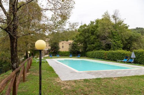 a swimming pool in a yard with a lamp at Romantic cozy house 15 min Arezzo piscina&bosco in Falciano