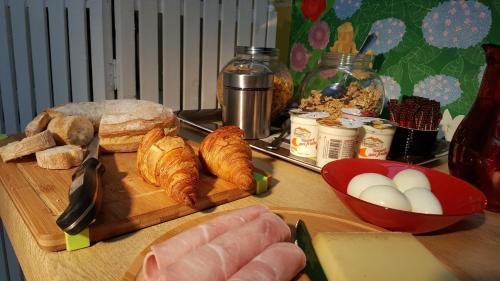 a table with croissants and eggs on a cutting board at Chambre D´hôtes Léonie & Restaurant in Druillat