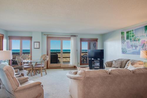 Una sala de estar con un sofá, una mesa y sillas. en Heron Cove 202S, en Nags Head