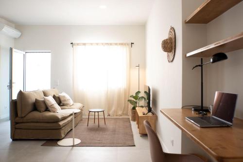 a living room with a couch and a desk with a laptop at Outsite Sagres in Sagres