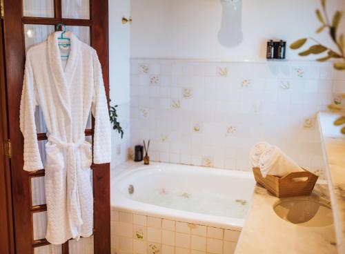 a bath tub in a bathroom with a robe on a door at Smart Hotel Reserva Campos do Jordão in Campos do Jordão