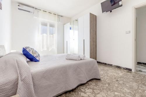 a white bedroom with a bed with blue pillows at Blanche Apartments in Porto Torres