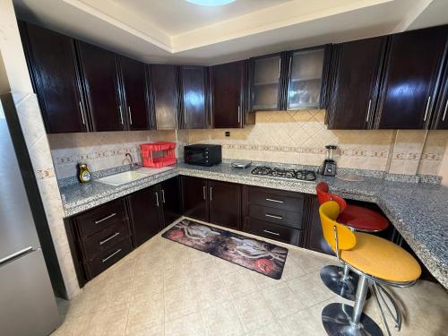 Una cocina con gabinetes de madera y encimera. en Appartement confort et lumineux, en Agadir