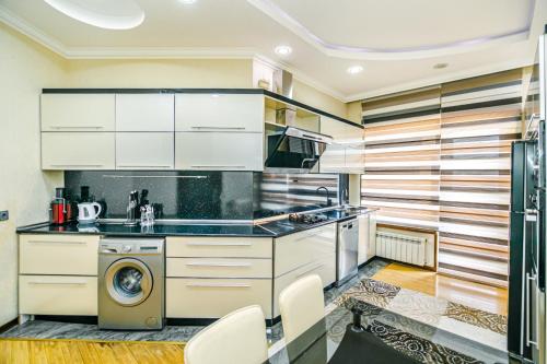 Una cocina con gabinetes blancos y lavadora y secadora. en IMPEX Apartment, en Baku