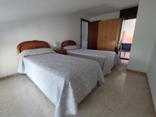a bedroom with two beds with white comforters at La Casa de Tito y Cosi in Noja