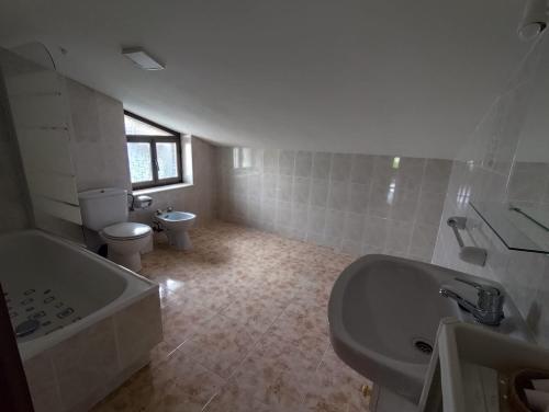 a bathroom with a tub and a toilet and a sink at La Casa de Tito y Cosi in Noja