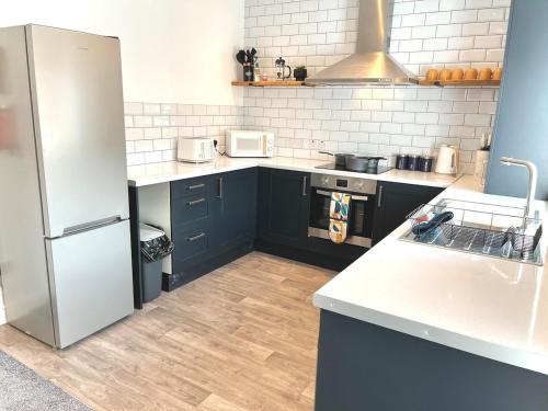 a kitchen with blue cabinets and a white refrigerator at Ideal 4 Bed Home sleeps 7 Nr Middlebrook Stadium in Lostock
