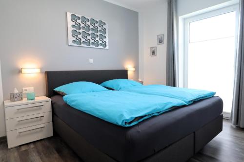 a bedroom with a large bed with blue sheets at ROBERTA - mit Terrasse und Sauna in Diemelsee