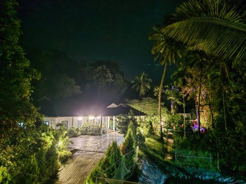 a night view of a resort with a pool and palm trees at Green BOB Villa in Sultan Bathery